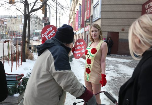 Courtney Shwetz sells the virtues of being vegan to a passer-by by handing out free vegan pizza in only short dresses in front of Portage Place Wednesday.   See Bartley Kives story.  Dec 03,  2014 Ruth Bonneville / Winnipeg Free Press