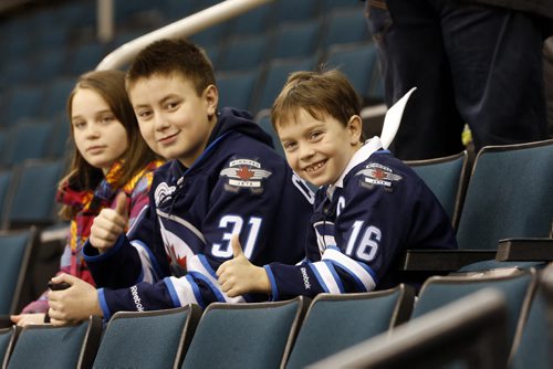 LOCAL - Jets autographed stick . MTS Centre.  Eight-year-old Connor  McDaniel (wearing Jets jersey #16 ) meets 13-year-old Evan Chartrand (wearing Jets Jersey #31) , the Äúmystery boyÄù who picked up Jets autographed stick dropped over the glass by Mark Scheifele and gave it to the younger boy it was intended for. In pic sitting with his sister Kaitlyn McDaniel age 10 watching the Jets practice. After practice photo of Scheifele and the boys (Scheifele will be presenting Evan with a gift for his graciousness, probably his autographed stick. FOR Sinclair columnDec. 4 2014 / KEN GIGLIOTTI / WINNIPEG FREE PRESS