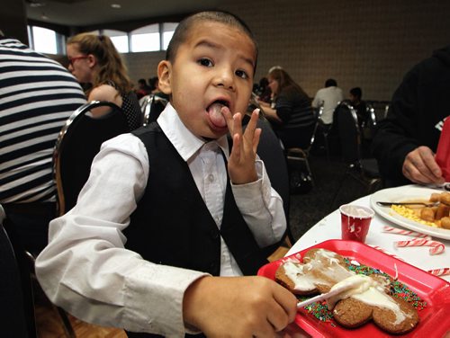 George Traverse, 5, licks his fingers while decorating his gingerbread cookie during a Christmas breakfast for kids and their family who have been through heart surgery at the Clarion Hotel Sunday morning.  141207 December 07, 2014 Mike Deal / Winnipeg Free Press
