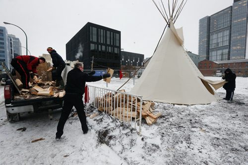 Stdup Scared Fire - Members of the Downtown BIz unload wood for the Sacred Fire to be lite inside the Tee Pee .Stdup DOWNTOWN IGNITES A SACRED FIRE IN HONOUR OF ASSEMBLY OF FIRST NATIONS CONFERENCE: DEC. 8 Downtown Winnipeg Äì Kevin Settee, an Ojibway Cree youth from Matheson Island and University of Winnipeg student, will be the Fire Keeper and Pipe Carrier of the Sacred Fire.A sacred fire will be lit on December 8 at 9:00 a.m. at the beginning of what will be a full-day of ceremonies in honour of the Assembly of First Nations (AFN) Special Chiefs Assembly.The  Sacred Fire is in honour of AFN Special Chiefs Assembly .The Pipe ceremony and lighting of Sacred Fire on Dec. 8 at 9:00 a.m. former Carlton Inn (St. Mary & Carlton)ÄúPrayers and intentions are offered through the fire with an offering of tobacco into the fire,Äù says Lisa Meeches, Executive Director of Manito Ahbee. ÄúThe sacred fire welcomes all to come and join and be a part of the ceremonies.ÄùKevin, along with other student volunteers and members of the Downtown Winnipeg BIZ will keep the fire burning 24 hours a day, until the AFN Special Chiefs Assembly concludes on Dec. 11.3,000 delegates of the Assembly of First Nations Special Chiefs Assembly will be arriving in  downtown Winnipeg.Äù. Dec. 8 2014 / KEN GIGLIOTTI / WINNIPEG FREE PRESS
