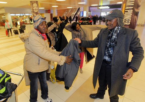 LOCAL - Zeleke Eliso Tuloro greets his family at Winnipeg James Armstrong Richardson International Airport. They are newcomers. Zeleke Eliso Tuloro meeting his family for the first time in 12 years  Teacher Zeleke Eliso Tuloro fled Ethiopia in 2002 as a political opposition party member targeted by military government  his wife and 3 kids stayed. Zeleke arrived in Winnipeg Dec. 12, 2012. In Wpg hes been working as a security guard to raise money to sponsor his family to join him. Here he passes his son Nathenael a winter parka. BORIS MINKEVICH / WINNIPEG FREE PRESS December 11, 2014