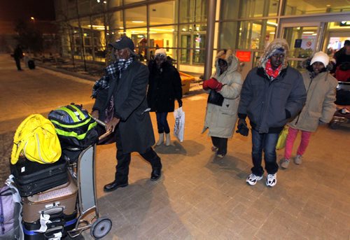 LOCAL - Zeleke Eliso Tuloro and his family exits in the cold winter night in Winnipeg. Winnipeg James Armstrong Richardson International Airport. Zeleke Eliso Tuloro meeting his family for the first time in 12 years  Teacher Zeleke Eliso Tuloro fled Ethiopia in 2002 as a political opposition party member targeted by military government  his wife and 3 kids stayed. Zeleke arrived in Winnipeg Dec. 12, 2012. In Wpg hes been working as a security guard to raise money to sponsor his family to join him. His family is youngest daughter Bethelihem, son Nathenael, oldest daughter Kalkidan, and wife named Zenebach. BORIS MINKEVICH / WINNIPEG FREE PRESS December 11, 2014