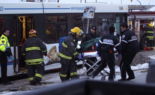 Winnipeg Fire Paramedics take an injured person from one the two Winnipeg Transit Buses that collided on Mapleglen Dr. Monday morning. Wayne Glowacki / Winnipeg Free Press Dec.15 2014