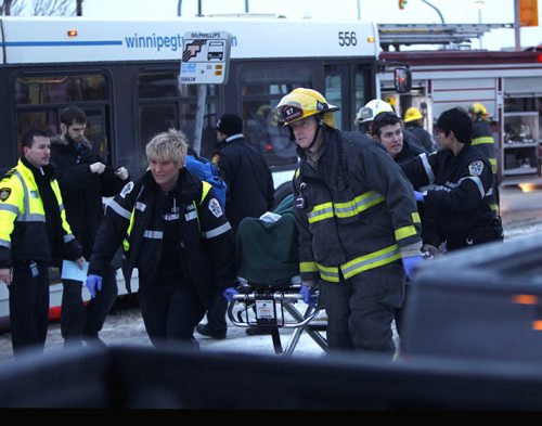 Winnipeg Fire Paramedics take an injured person from one the two Winnipeg Transit Buses that collided on Mapleglen Dr. Monday morning. Wayne Glowacki / Winnipeg Free Press Dec.15 2014