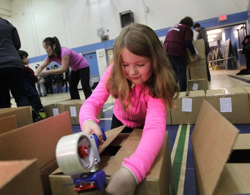 Nine-year-old Julia Lukowich helps tape up Christmas Hampers with many other volunteers at R.B. Russell School Saturday where they  filled and delivered 200 CHRISTMAS HAMPERS to  First Nations people. See story.  Dec 20,  2014 Ruth Bonneville / Winnipeg Free Press