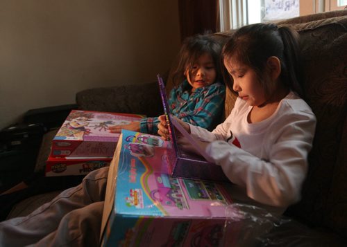 Seven-year-old Dreanna Sinclair (righty) and her little sister Shaelynn  - 5yrs, opens gifts they just received from Ma Mawi Wi Chi Itata Centre 12th Annual Christmas Hamper Drive which took place at R.B. Russell School Saturday morning.     See story.  Dec 20,  2014 Ruth Bonneville / Winnipeg Free Press