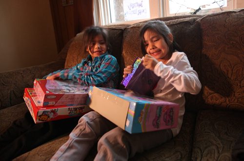 Seven-year-old Dreanna Sinclair (right) and her little sister Shaelynn  - 5yrs, opens gifts they just received from Ma Mawi Wi Chi Itata Centre's 12th Annual Christmas Hamper Drive which took place at R.B. Russell School Saturday morning.     See story.  Dec 20,  2014 Ruth Bonneville / Winnipeg Free Press