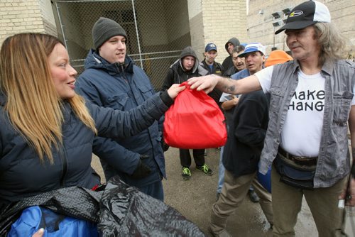 From Left-  Kay Lizon, center, and Chris Smith of The Gary Effect, hand out presents to people on the street in front of Siloam Mission Tuesday . They started handing out gifts Dec. 22 and are continuing through today. ( Eds Kay also goes with Karen as first name-match with reporters story) - See Brittany Hobson story Dec 23, 2014   (JOE BRYKSA / WINNIPEG FREE PRESS)