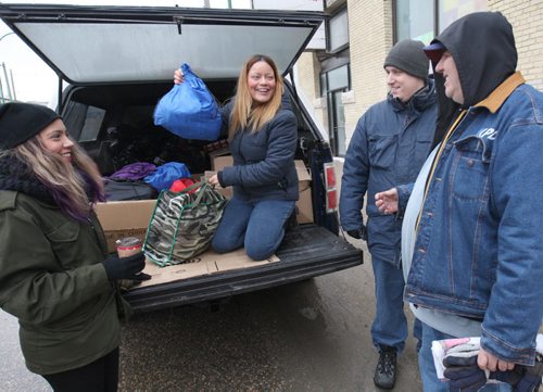L to R- Jessica Boittiaux Kay Lizon, center, and Chris Smith of The Gary Effect, hand out presents to people on the street in front of Siloam Mission Tuesday ( fellow in jean jacket, R, is receiving gift). They started handing out gifts Dec. 22 and are continuing through today. ( Eds Kay also goes with Karen as first name-match with reporters story) - See Brittany Hobson story Dec 23, 2014   (JOE BRYKSA / WINNIPEG FREE PRESS)