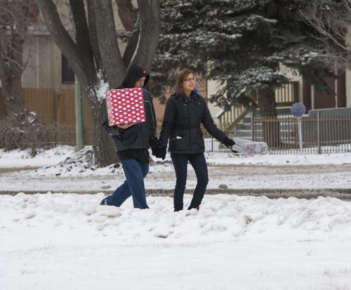 121225 Winnipeg - DAVID LIPNOWSKI / WINNIPEG FREE PRESS  Wallace Audy carries a wrapped Christmas present as he and girlfriend Marie Catcheway make their way down Provencher Blvd Christmas Day on the way to celebrate the holiday with family and friends.
