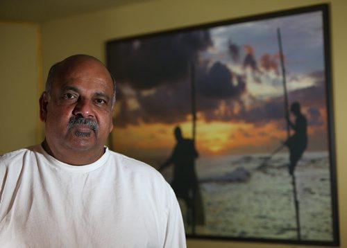Peter Bastians, the former head of the Sri Lankan Association of Manitoba, stands in front of a photo of the southern Sri Lankan region of Galle that was ravaged by the Dec. 26, 2004 tsunami that killed more than 250,000 people. Bastians was photographed in his home on Dec. 27, 2014. Photo by Jason Halstead/Winnipeg Free Press