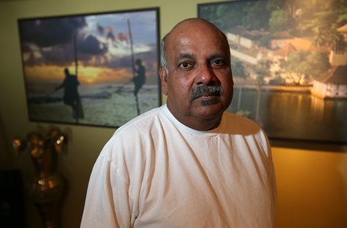 Peter Bastians, the former head of the Sri Lankan Association of Manitoba, stands in front of a photo of the southern Sri Lankan region of Galle that was ravaged by the Dec. 26, 2004 tsunami that killed more than 250,000 people. Bastians was photographed in his home on Dec. 27, 2014. Photo by Jason Halstead/Winnipeg Free Press