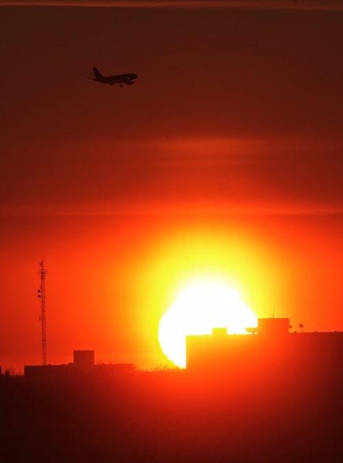 A plane is silhouetted by the sun as it approaches the Winnipeg James Armstrong airport late Sunday afternoon.  141228 December 28, 2014 Mike Deal / Winnipeg Free Press