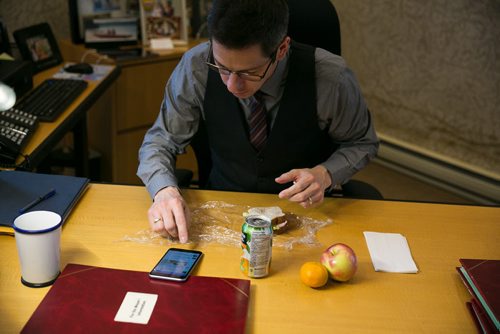 11:07:17 AM - Lunch Bowman eats his lunch (a ham sandwich made by Tracey the night before) at his desk while he scans social media.   141215 - Monday, December 15, 2014 - (Melissa Tait / Winnipeg Free Press)