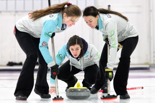 Skip Beth Peterson throws a rock with Lead Breanne Yozenko (left) and Second Melissa Gordon (right) as sweepers just before winning the Junior Women's Provincial Championship at the Assiniboine Memorial Curling Club Wednesday evening.  141231 December 31, 2014 Mike Deal / Winnipeg Free Press