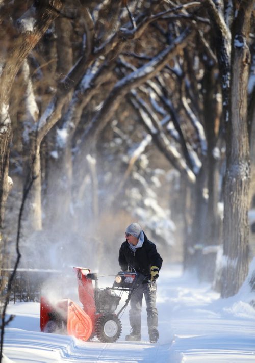 A man uses a snowblower in front of a house on Harvard Avenue, Saturday, January 3, 2015. (TREVOR HAGAN/WINNIPEG FREE PRESS)