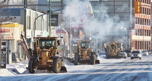 Snow clearing crews make their was along Portage Avenue Sunday morning after a weekend snowstorm dropped around 14cm of the white stuff.  150104 January 04, 2015 Mike Deal / Winnipeg Free Press