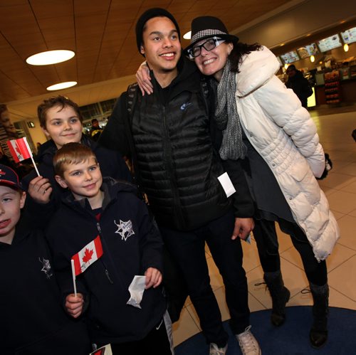 Team Canada Jr Hockey star Madison Bowey posed with members of the Starbuck Hockey Acadamy, his old school,  while an impatient mom Pam, snuck in from behind for a kiss and a hug Tuesday afternoon at Richardson Airfield Tuesday afternoon. See Melissa Martin's story. January 6, 2015 - (Phil Hossack / Winnipeg Free Press)