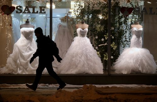 A man rushes to catch a bus past a display of wedding dresses on Portage Avenue, Wendesday, January 7, 2015. (TREVOR HAGAN/WINNIPEG FREE PRESS)
