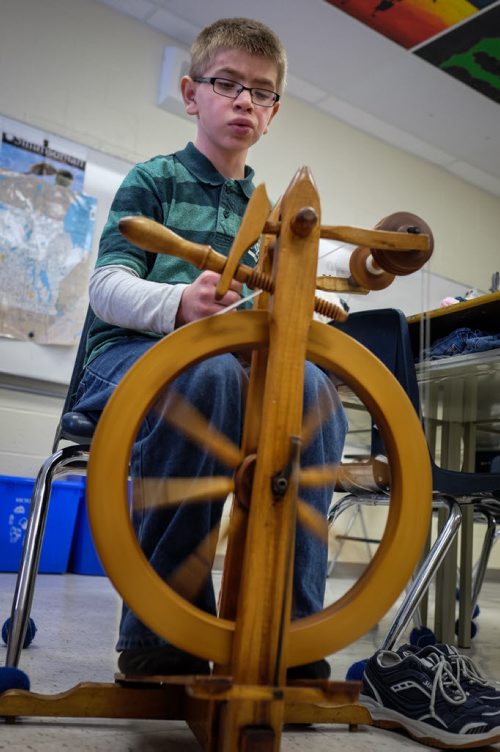 Michael Elias, 12, spins yarn on one of the four spinning wheels the class has access to. Elaine Owen, a teacher at Miami School in Miami, Manitoba has undertaken a huge project to teach her students some core values. Over the last six months, she has gathered raw wool and shown her students the process through washing, carding, dyeing and spinning the wool and then using looms, making mittens, scarves, etc. Elaine has four spinning wheels in her classroom and the students are donating their crafted items to a local shelter.  150113 - Wednesday, January 14, 2015 -  (MIKE DEAL / WINNIPEG FREE PRESS)