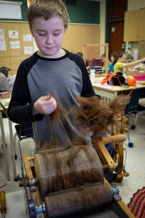 William Dyck, 11, pulls out alpaca wool from one of the drum carding machines. The alpaca wool gets put through the machine two or three times before being spun into yarn. Elaine Owen, a teacher at Miami School in Miami, Manitoba has undertaken a huge project to teach her students some core values. Over the last six months, she has gathered raw wool and shown her students the process through washing, carding, dyeing and spinning the wool and then using looms, making mittens, scarves, etc. Elaine has four spinning wheels in her classroom and the students are donating their crafted items to a local shelter.  150113 - Wednesday, January 14, 2015 -  (MIKE DEAL / WINNIPEG FREE PRESS)