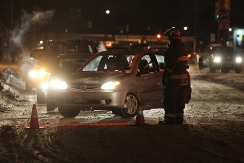 A firefighter directs traffic off of South bound McPhillips.  Several people were sent to hospital after a three vehicle accident on McPhillips at Magnus Avenue shortly after 6pm Wednesday. No word on the extent of the injuries.  150114 January 14, 2015 Mike Deal / Winnipeg Free Press
