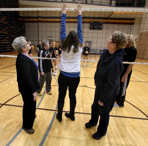 Showing off the historic hardware, (left to right) Donna Dawson left, Sharon Martin right, watch as Joan Chaput checks the height of the net at a Bison's team workout Wednesday. They recall their days with the University of Manitoba Bisonettes womens volleyball team that won the first ever official Canadian national championship. See Melissa Martin's story. January 14, 2015 - (Phil Hossack / Winnipeg Free Press)