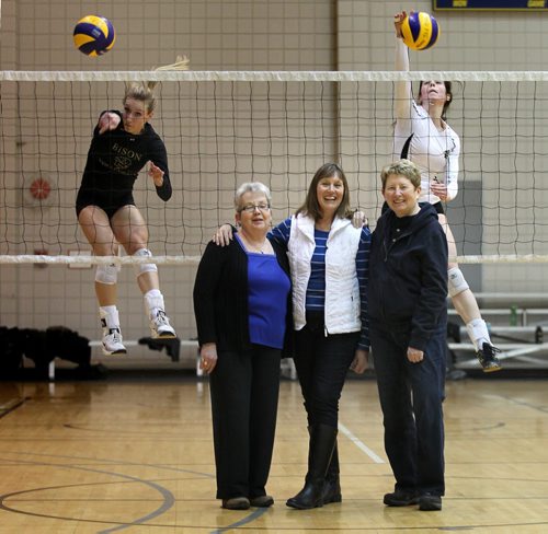 Left to right, Donna Dawson, Joan Chaput and  Sharon Martin pose while U of M Bison's slam volleyballs over their head Wednesday afternoon. The trio played for the U of M's 1970-71 Bisonettes who won the first ever Official Canadian Women's Volleyball Championships. See Melissa Martin story. January 14, 2015 - (Phil Hossack / Winnipeg Free Press)