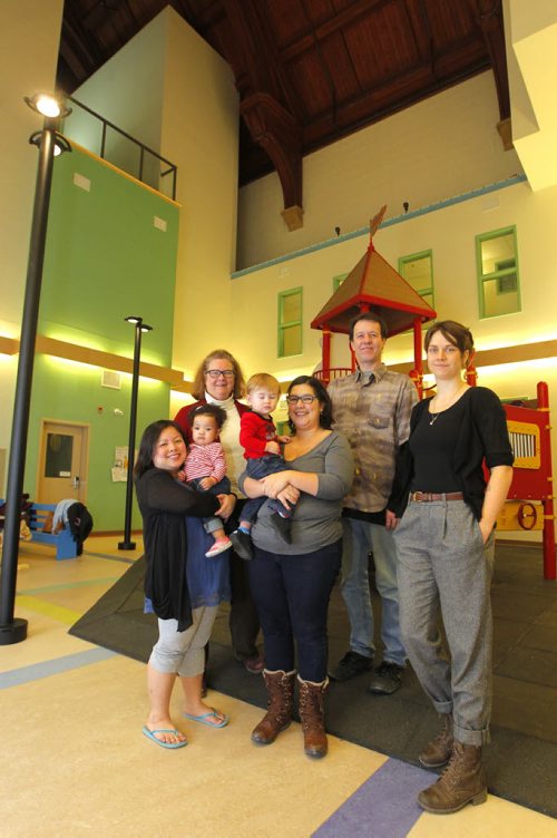 LOCAL - West End Commons (formerly St. Matthews Anglican Church). The old church has been converted into apartments, a playground, community meeting spaces and its new smaller sanctuary is now home to five church groups. Left to right, resident Oanh Pham and one year old Hannah Ike, Cathy Campbell, vice chair of the board of West End Commons and priest of St. Matthews Anglican Church, resident Erika Frey with s 15 month old  son Bram, resident Craig Sharpe, and Jenna Drabble, community connector for the West End Commons. CAROL SANDERS yarn. BORIS MINKEVICH/WINNIPEG FREE PRESS. JANUARY 16, 2015