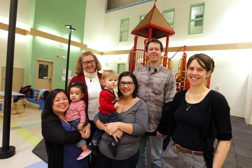 LOCAL - West End Commons (formerly St. Matthews Anglican Church). The old church has been converted into apartments, a playground, community meeting spaces and its new smaller sanctuary is now home to five church groups. Left to right, resident Oanh Pham and one year old Hannah Ike, Cathy Campbell, vice chair of the board of West End Commons and priest of St. Matthews Anglican Church, resident Erika Frey with s 15 month old  son Bram, resident Craig Sharpe, and Jenna Drabble, community connector for the West End Commons. CAROL SANDERS yarn. BORIS MINKEVICH/WINNIPEG FREE PRESS. JANUARY 16, 2015