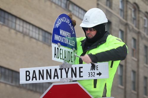 A city of Winnipeg worker puts up and new sign tittle "Honourary Winnipeg Innovation Ally" sign on top of the Adelaide St. and Bannatyne Ave. Sign Friday afternoon after unveiling by Mayor Brian Bowman at AssentWorks.  Jan 16, 2015 Ruth Bonneville / Winnipeg Free Press