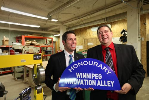 Winnipeg Mayor Brian Bowman and Michael Legary with Startup Winnipeg, hold new sign entittled  "Honourary Winnipeg Innovation Ally"  that was put on top of the  Adelaide St. and Bannatyne Ave. Sign at unveiling Friday.   See Story.  Jan 16, 2015 Ruth Bonneville / Winnipeg Free Press