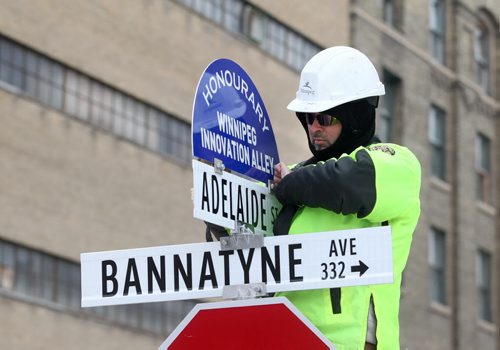 A city of Winnipeg worker puts up and new sign entittled "Honourary Winnipeg Innovation Ally" sign on top of the Adelaide St. and Bannatyne Ave. Sign after unveiling by Mayor Brian Bowman Friday.   Jan 16, 2015 Ruth Bonneville / Winnipeg Free Press