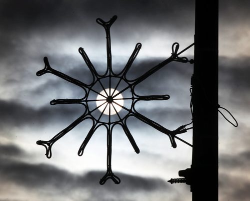 The sun peaks its way through clouds behind a snowflake decoration on Marion St in Winnipeg Monday afternoon-Standup photo- Jan 19, 2015   (JOE BRYKSA / WINNIPEG FREE PRESS)