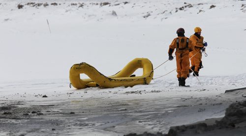 A couple of fire paramedics pull on a water rescue craft during training under the Main Street bridge close to The Forks Monday afternoon.  150119 January 19, 2015 Mike Deal / Winnipeg Free Press