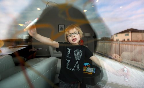 Four yr old Cian Anaka stands back to admire his masterpiece after drawing on the family room window with his markers Monday. See Mary Agnes story re: Child Care. January 19, 2015 - (Phil Hossack / Winipeg Free Press)