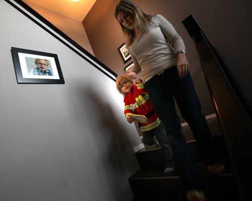 Four yr old Cian Anaka and his mom Kristi make their way downstairs past a portrait of Anaka Monday. See Mary Agnes story re: Child Care. January 19, 2015 - (Phil Hossack / Winipeg Free Press)