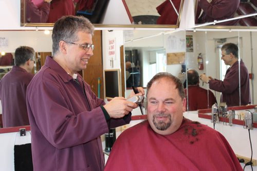 044 - 0 47 - Grant Hurrell, aka Hymie the Haircutter in Neepawa, gives customer Brian Scott a trim. Hurrell is a volunteer RCMP constable on weekends. BILL REDEKOP/WINNIPEG FREE PRESS Jan 21, 2015
