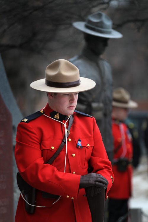 Cst Mike Eady's Stetson mirrors the memorial as he stands at the Portage ave "D" Division's Winnipeg HQ Monday afternoon.  A wreath was layed in memorium of Cst David Wyn, who was shot and killed in Alberta last week. Cst Eady is a member of Higheway Traffic Services based in Virden Mb.  See story. January 26, 2015 - (Phil Hossack / Winnipeg Free Press)