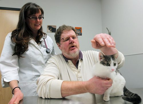 PET PAGE - The trials and tribulations of getting a pet cat to swallow a pill. (L) Humane Society veterinarian Dr. Erika M. Anseeuw with(R) WFP's Doug Speirs "pilling" a cat. Pilling is administering drugs to a cat in the form of a pill. BORIS MINKEVICH / WINNIPEG FREE PRESS  Jan. 27, 2015