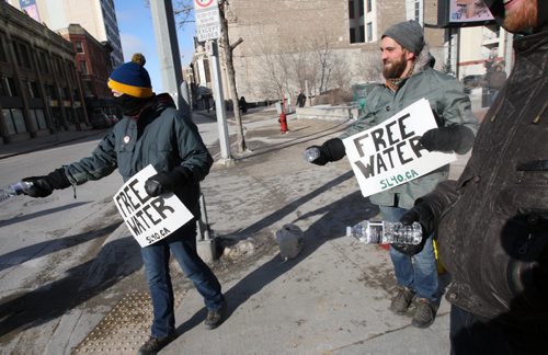 Chuck Wright, right- grey hat, and a small group of concerned citizens handed out bottles of water with a statement on the labels to highlight the irony of a 17-Year Long Boil Water Advisory in Shoal Lake #40 the source of Winnipegs drinking water in Winnipeg Thursday near Portage and Main- Winnipeg has gone 1 1/2 days while the Shoal Lake First Nation has gone 6205 days  or 17 years on a boil order advisory. The band is seeking a all-season road to the community would make building a water treatment plant affordable-See Adam Wazny story- Jan 29, 2015   (JOE BRYKSA / WINNIPEG FREE PRESS)