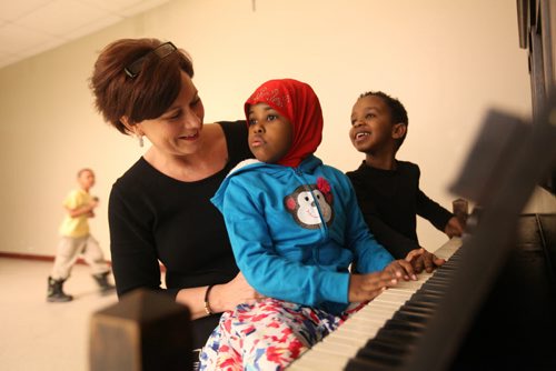 Khadija Hassan sits on Theresa Oswald's lap as she tries to play the piano along with Ibrahim Ahmed just prior to Oswald's press conference    announcing more supports for new Canadians Friday held at the Phillippine Canadian Centre. See Story. Jan 30, 2015 Ruth Bonneville / Winnipeg Free Press