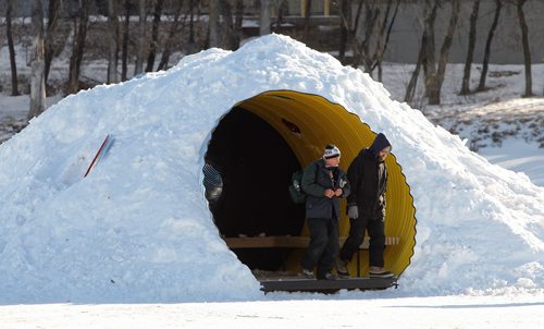 Pedestrians take advantage of a warming hut on the River Trail Sunday morning. The hut is called "The Hole Idea" and is a large snow covered corrugated tunnel that has a number of smaller tubes that act as windows.  150201 February 01, 2015 Mike Deal / Winnipeg Free Press