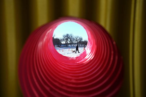 A police officer takes a young K9 pup out for a quick walk on the ice of the River Trail as seen through a window of a warming hut on the River Trail Sunday morning. The hut is called "The Hole Idea" and is a large snow covered corrugated tunnel that has a number of smaller tubes that act as windows.  150201 February 01, 2015 Mike Deal / Winnipeg Free Press