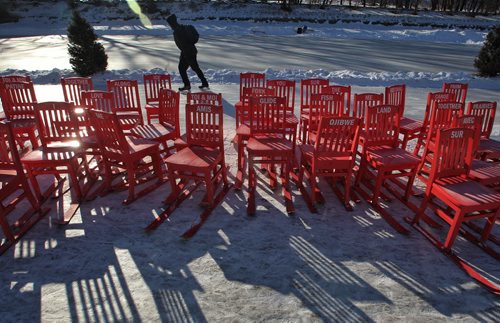 A person skates past a bunch of chairs equipped with skies for use on the River Trail Sunday morning.  150201 February 01, 2015 Mike Deal / Winnipeg Free Press