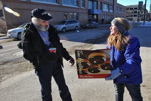 Marsha Eldridge holds up a box of doughnuts for Rodger Charron outside Booth Centre on Henry Avenue Sunday afternoon. Marsha and her husband Ron have been handing out hot drinks for those in need for years and today was no different, people were very happy to see them.  150201 February 01, 2015 Mike Deal / Winnipeg Free Press