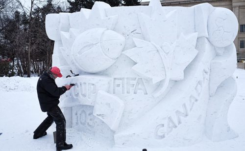 David MacNair puts the finishing touches on a snow-sculpture on the grounds of the Manitoba Legislative Building Monday afternoon. The sculpture marks the 2015 FIFA womenÄôs world cup on one side and the 2015 Grey Cup to be played in Winnipeg on another. FIFA and Grey Cup organizers will help Premier Greg Selinger unveil the snow masterpiece Tuesday morning. 150209 February 09, 2015 Mike Deal / Winnipeg Free Press