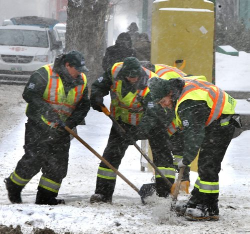 Members of the Downtown Winnipeg BIZ Metro Enviro-Team were hard at work keeping crossings clear for pedestrians as snow falls in Winnipeg Tuesday. Wayne Glowacki/Winnipeg Free Press Feb.10   2015