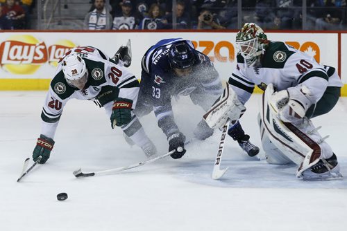 Winnipeg Jets' Dustin Byfuglien (33) draws a holding penalty on Minnesota Wild's Ryan Suter (20) as he was driving for the loose puck in front of Wild goaltender Devan Dubnyk (40) during second period NHL action in Winnipeg on Tuesday, February 10, 2015. (John Woods / WINNIPEG FREE PRESS)