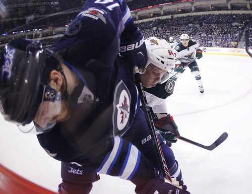 Minnesota Wild's Mikael Granlund (64) and Winnipeg Jets' Bryan Little (18) fight for the puck during second period NHL action in Winnipeg on Tuesday, February 10, 2015. (John Woods / WINNIPEG FREE PRESS)